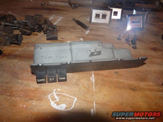 Car dashboard clock assembly with DATE, E/T, and TIME buttons. Part number 307 0132 visible
