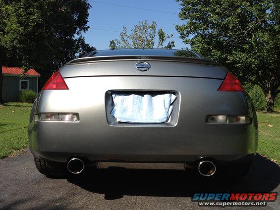 Gray Nissan 350Z rear view with dual exhaust pipes and a blue cloth covering the license plate area