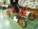 1906 Ford Model T - A vintage red touring car is displayed indoors, with a white car visible in the background.