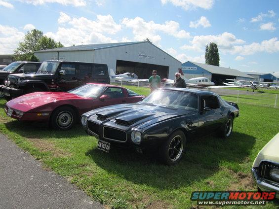 Black Pontiac Firebird with dual hood scoops and a license plate AN-393-XJ parked on grass
