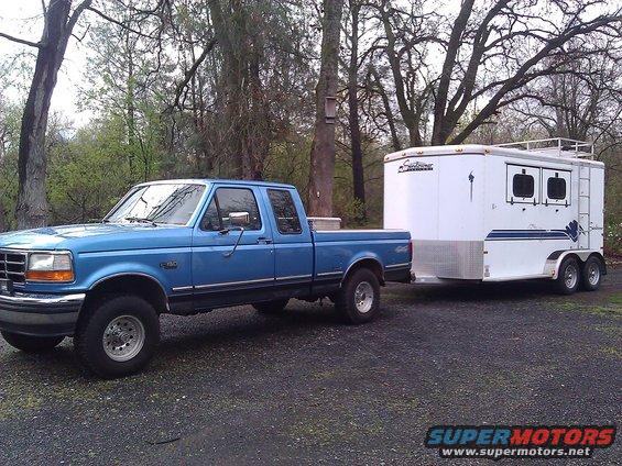 1992 Ford F-150 pickup truck, blue, towing a white trailer with two axles