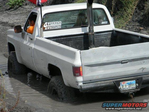 White pickup truck with tall exhaust pipe stuck in mud