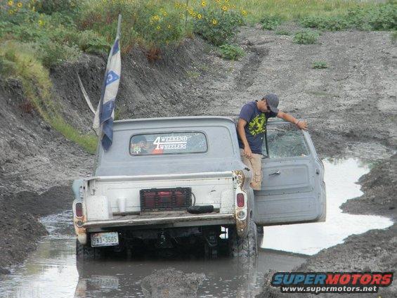 Gray pickup truck in mud, person exiting driver's side door