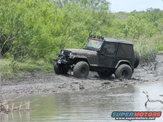 black Jeep Wrangler driving through mud and water