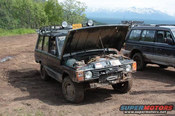 Black SUV with hood open, winch on front bumper, roof rack with lights