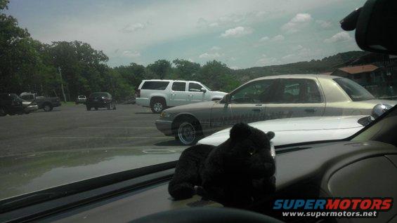 Side view of a silver Mercury Grand Marquis parked in a lot. A white SUV is behind it