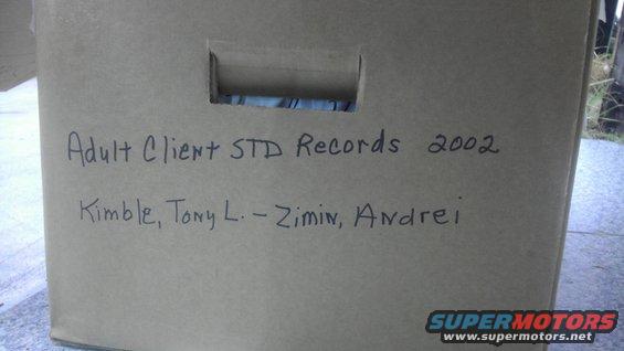 Cardboard box labeled 'Adult Client STD Records 2002' with names Kimble, Tony L. and Zimin, Andrei. Also has a Supermotors.net watermark
