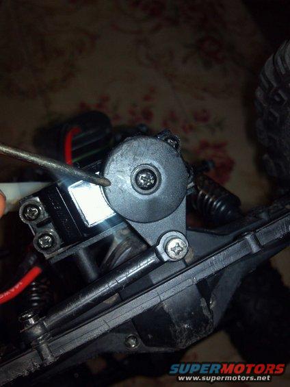 Black plastic servo horn on a remote control car chassis, being adjusted with a screwdriver