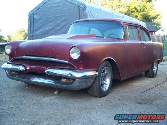 Maroon sedan with a hood scoop and chrome bumper, seen from a 3/4 front angle