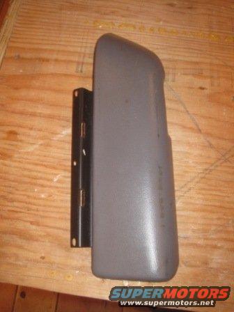 Gray plastic part with metal bracket attached, lying on a wooden surface