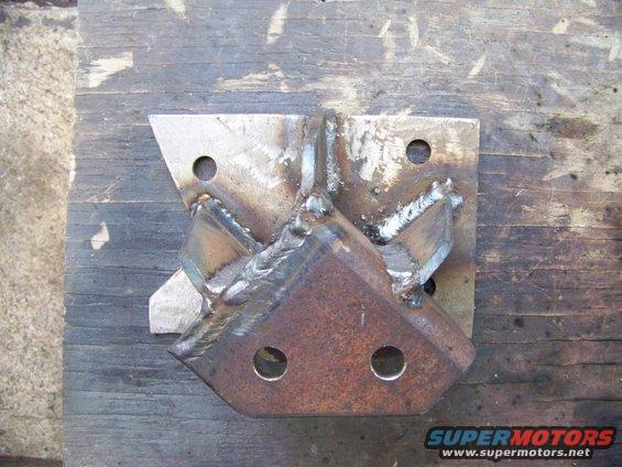Welded steel bracket with multiple mounting holes, resting on a wooden surface