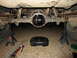 1992 Ford Bronco - Vehicle's rear differential is exposed and supported by jack stands, with tools and an oil pan nearby.