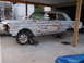 1971 Ford Ranchero - A heavily rusted light blue sedan sits on dollies under a carport, awaiting restoration.