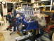 1971 Ford Ranchero - A powerful V8 engine with a supercharger and dual carburetors is displayed on a stand in a workshop.