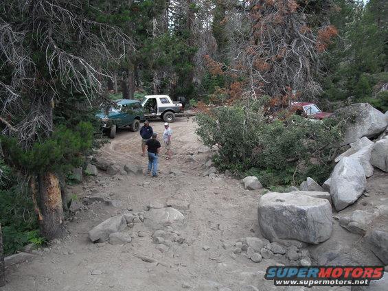 White Ford Bronco parked on a dirt road with trees and rocks