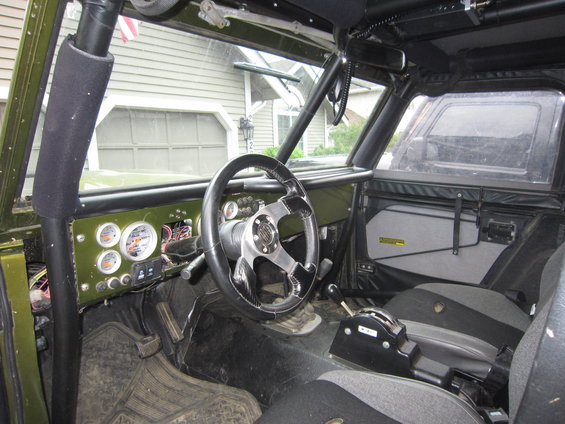 Off-road vehicle interior showing custom gauges, aftermarket steering wheel, and racing seats. Roll cage visible