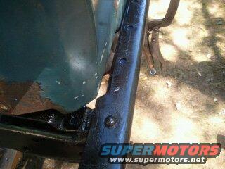 Close-up of black painted vehicle frame with green body panel attached