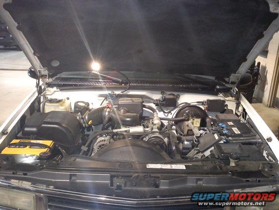 White 1997 Chevrolet Silverado 1500 engine bay with hood open, showing V8 engine components and battery