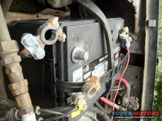 Close-up of a car battery with corroded terminals and wiring connected