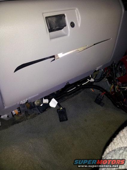 Vehicle interior showing a damaged glove compartment and exposed wiring under the dashboard