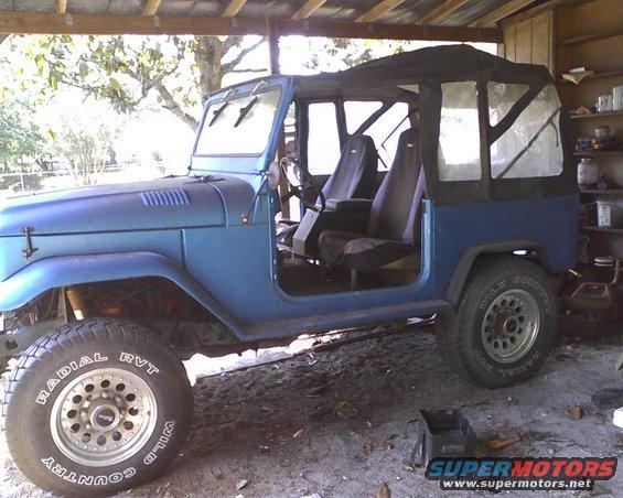 Blue 1969 Toyota Land Cruiser with soft top, open doors, and aftermarket wheels
