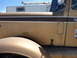 1959 Kenworth W900A - Side view of a tan truck's fender and door, with "KENWORTH" lettering visible on the panel.