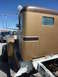 1959 Kenworth W900A - Side view of a brown and tan truck cab, with a pickup truck and concrete mixer in the background.