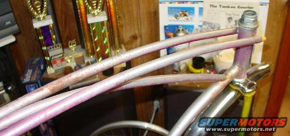 Silver and pink bicycle frame with rust spots, viewed from the side