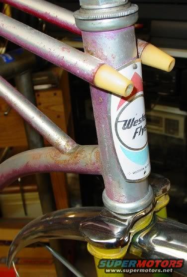 Close-up of a bicycle's head tube with a Western Flyer badge and chrome handlebars