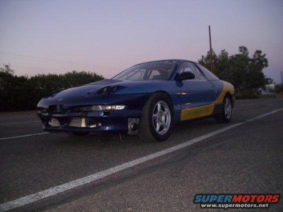Blue and yellow Ford Probe with hood scoops and aftermarket intercoolers parked on asphalt