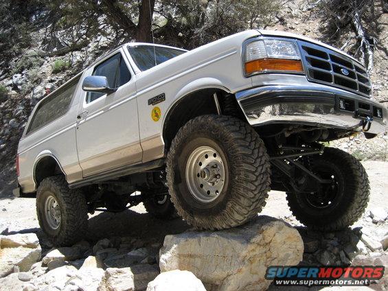 White Ford Bronco climbing over rocks on a trail