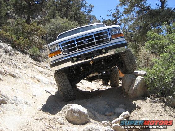 1996 Ford Bronco climbing over rocks on a dirt trail