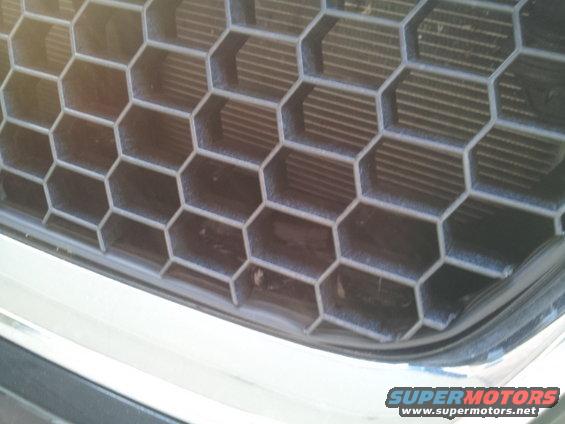 Close-up of a 2008 Subaru Legacy grille with honeycomb pattern and chrome trim