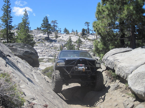 Black off-road truck with winch and custom bumper navigating a rocky trail