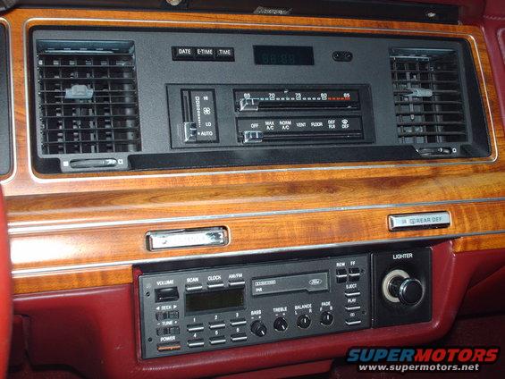 Car dashboard with wood trim, climate controls, radio, and lighter
