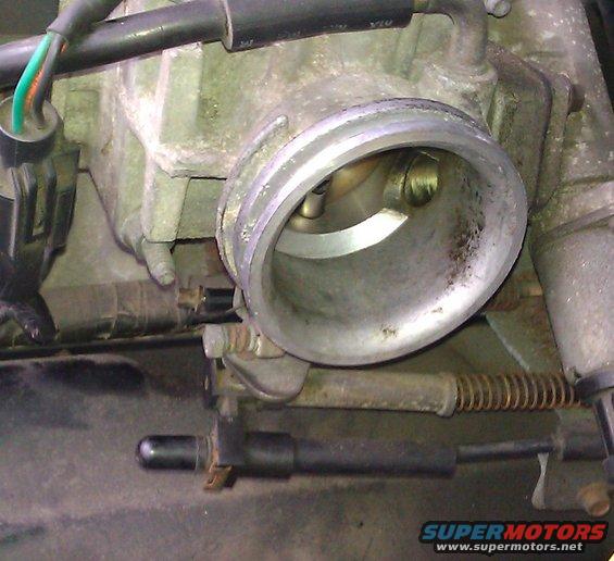 Close-up of a throttle body assembly with visible internal butterfly valve and linkage