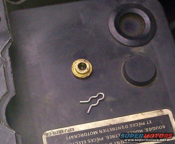 Brass grommet and metal clip on black plastic surface with text