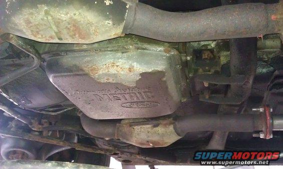 Underside of a vehicle showing the transmission pan with 'Automatic Transmission' and 'METRIC' visible, along with exhaust pipes