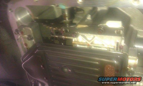 Transmission pan removed, showing valve body and some fluid. Visible internal components and bolts