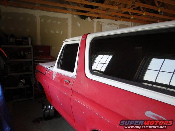 Side view of a red and white 1978 Ford Bronco undergoing restoration