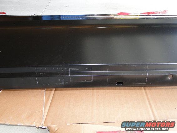 black metal panel with tape markings on it, sitting on cardboard