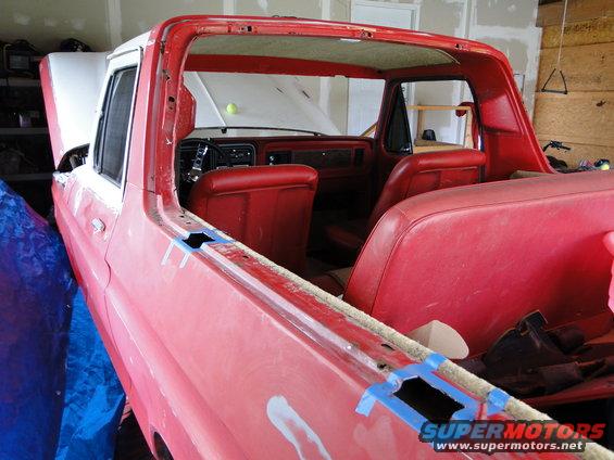 Red 1978 Ford Bronco interior with red seats and dashboard visible. Hood is up, and the vehicle appears to be undergoing restoration