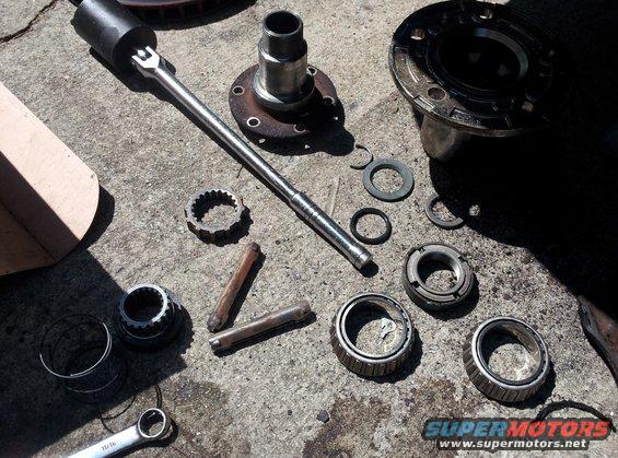 Wheel bearing kit and socket wrench on concrete. Includes hub, bearings, seals, and socket