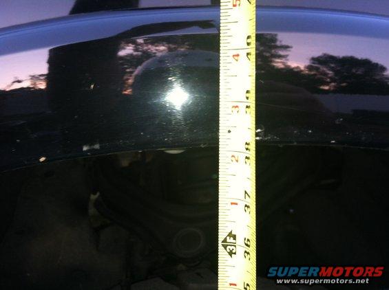 Measuring tape against black car body near wheel well