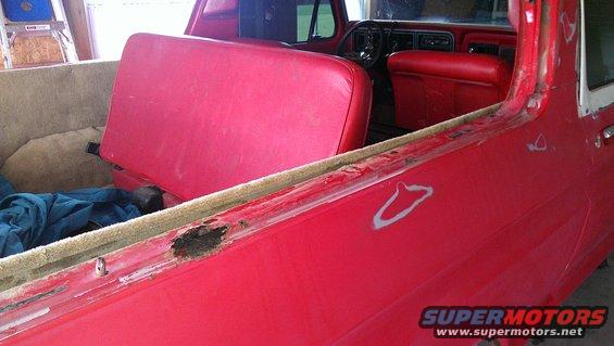 1978 Ford Bronco interior with red seats and dashboard visible, showing rust damage on the upper door frame