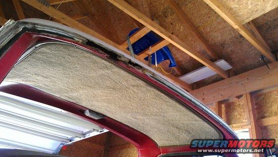 Close-up of a red vehicle's headliner and roof structure, showing insulation and exposed framing