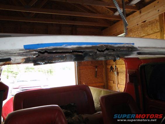 Rusted roof edge with blue tape, red interior visible