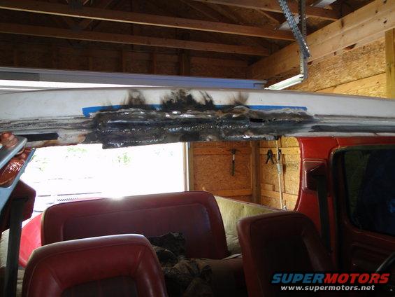 Close-up of rusted metal being repaired on the roof of a red vehicle interior