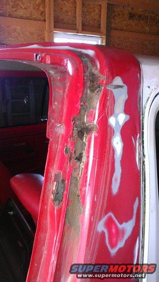 Red vehicle door frame with significant rust and body filler patches