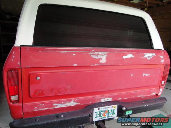 Rear of a red 1978 Ford Bronco with a white top, showing primer spots and a Florida license plate